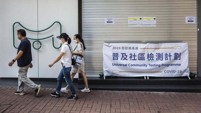 Sejumlah orang berjalan melewati pusat pengujian virus corona COVID-19 di Hong Kong, Selasa (1/9/2020). Hong Kong mulai melakukan tes massal virus corona COVID-19. (ISAAC LAWRENCE/AFP)