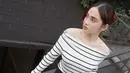 Syifa mengenakan atasan off shoulder warna putih bergaris hitam dipadukan celana hitam panjang belt tali. Ia tampil dengan flat shoes berpita dan anting-anting emas. [@syifahadju]