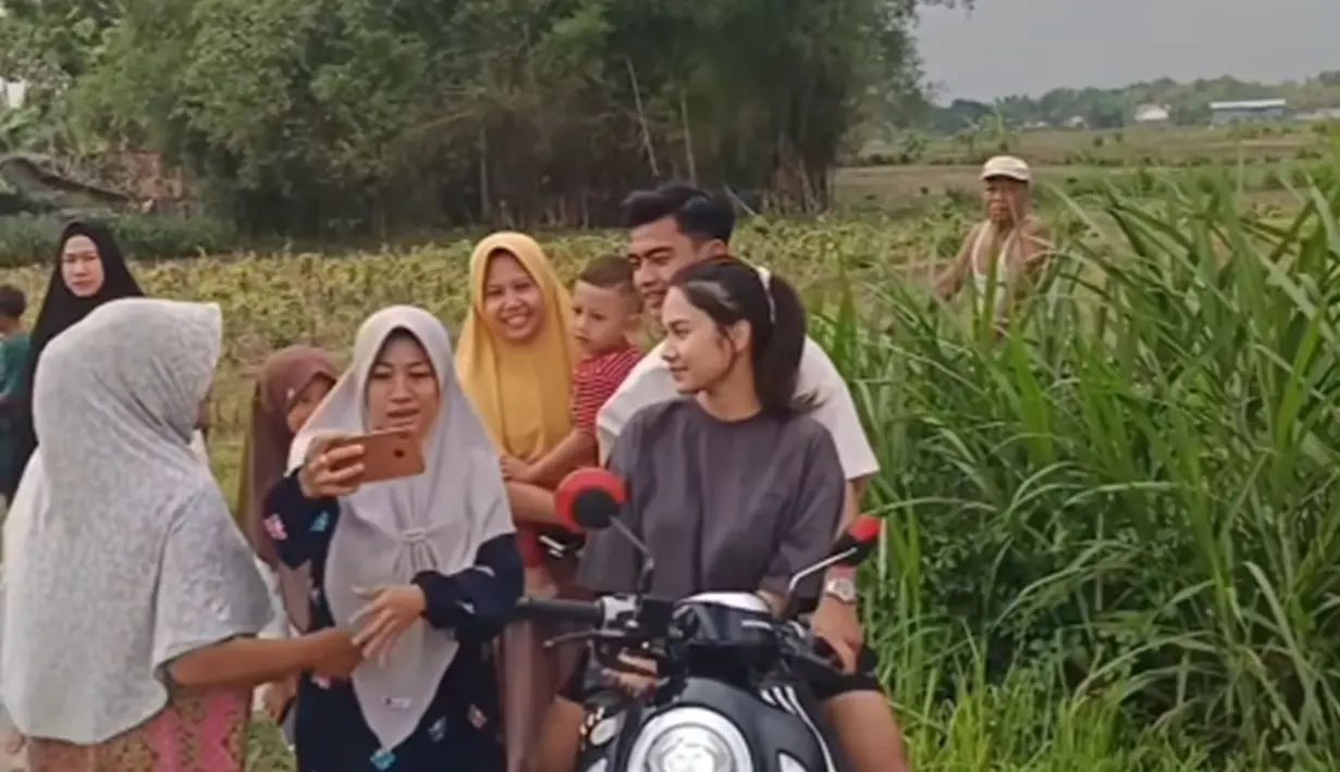 Ramah kepada warga, ini adalah momen Azizah dan Arhan meladeni warga yang minta foto bareng. Usai berfoto, Arhan dan Azizah pamit untuk jalan-jalan lagi. Terlihat banyak warga yang senang akan kehadiran Arhan dan Azizah di Blora. Usai menikah dengan Arhan, Azizah Salsha memang makin dikenal dan tak sedikit yang meminta foto dengan Azizah. (Liputan6.com/IG/@/arhanazizah.official)