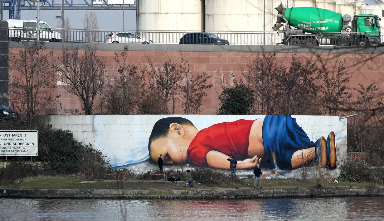 Grafiti raksasa buatan Justus Becker dan Oguz Sen bergambar Aylan Kurdi, bocah Suriah yang jasadnya ditemukan di pantai barat daya Turki pada September 2015, terpampang di sebuah tembok di sungai Main, Frankfurt, Jerman, 10 Maret 2016. (Daniel ROLAND/AFP)