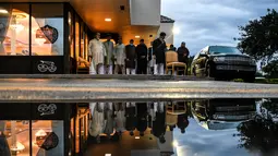 Refleksi pria Muslim terlihat dari genangan air saat mereka salat di trotoar di luar restoran selama bulan suci Ramadhan di Lauderhill, Florida, Jumat (30/4/2021). Selama puasa Ramadhan, umat Islam tidak makan, minum, atau aktivitas seksual dari fajar hingga matahari terbenam. (CHANDAN KHANNA/AFP)