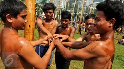 Peserta saling memberi semangat saat mengikuti lomba panjat pinang massal dalam rangka merayakan HUT Kemerdekaan RI ke-71 di lapangan ex Golf Driving Range Senayan, Jakarta, Rabu (17/8). (Liputan6.com/Gempur M Surya)