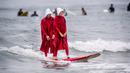 Erik dan April berselancar menggunakan kostum karakter dari The Handmade's Tale di Newport Beach, California, 28 Oktober 2017. Acara ini untuk merayakan Halloween yang jatuh pada tanggal 31 Oktober. (Paul Rodriguez/The Orange County Register via AP)