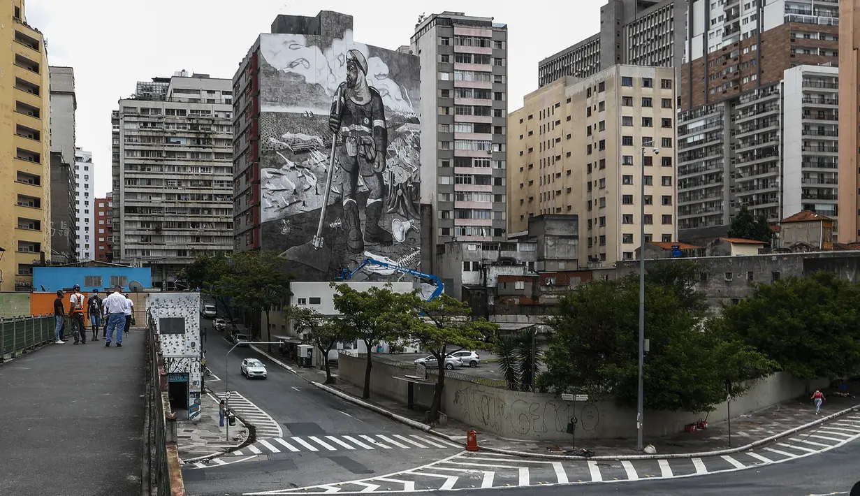 Mural berjudul "The Forest Brigadir" menggunakan abu kebakaran hutan Amazon oleh seniman Thiago Mundano, menutupi kompleks apartemen di Sao Paulo, Brasil, Jumat (15/10/2021). Mural bergambar petugas damkar yang berdiri di tengah peristiwa deforestasi, kebakaran, dan hewan mati. (AP/Marcelo Chello)
