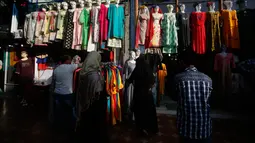Dua wanita muslim Kashmir mencari pakaian sebelum Idul Fitri di Srinagar, Kashmir yang dikuasai India (2/6/2019). Idul Fitri, menandai berakhirnya bulan puasa Ramadan. (AP Photo/Mukhtar Khan)