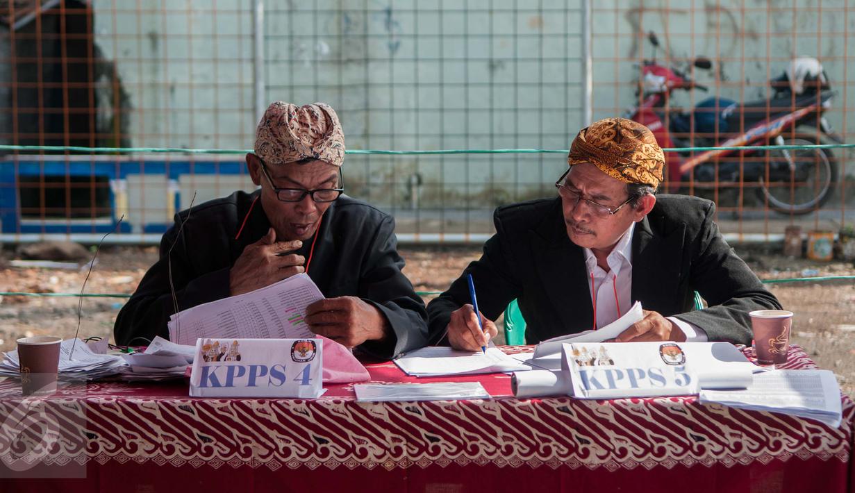 Petugas KPPS mengenakan pakaian adat dan belangkon melihat lembaran data pemilih di TPS 14 Cipinang Besar Selatan, Jakarta, Rabu (19/4). Petugas KPPS menggunakan pakaian adat tersebut agar warga tertarik untuk mencoblos. (Liputan6.com/Gempur M. Surya)