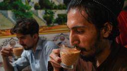 Pria Pakistan meminum secangkir teh di sebuah restoran di Islamabad, Rabu (15/6/2022). Pakistan diketahui merupakan salah satu negara importir teh terbesar dunia yang kini tengah bergulat dengan inflasi yang melonjak dan rupee yang terdepresiasi dengan cepat. (Aamir QURESHI / AFP)