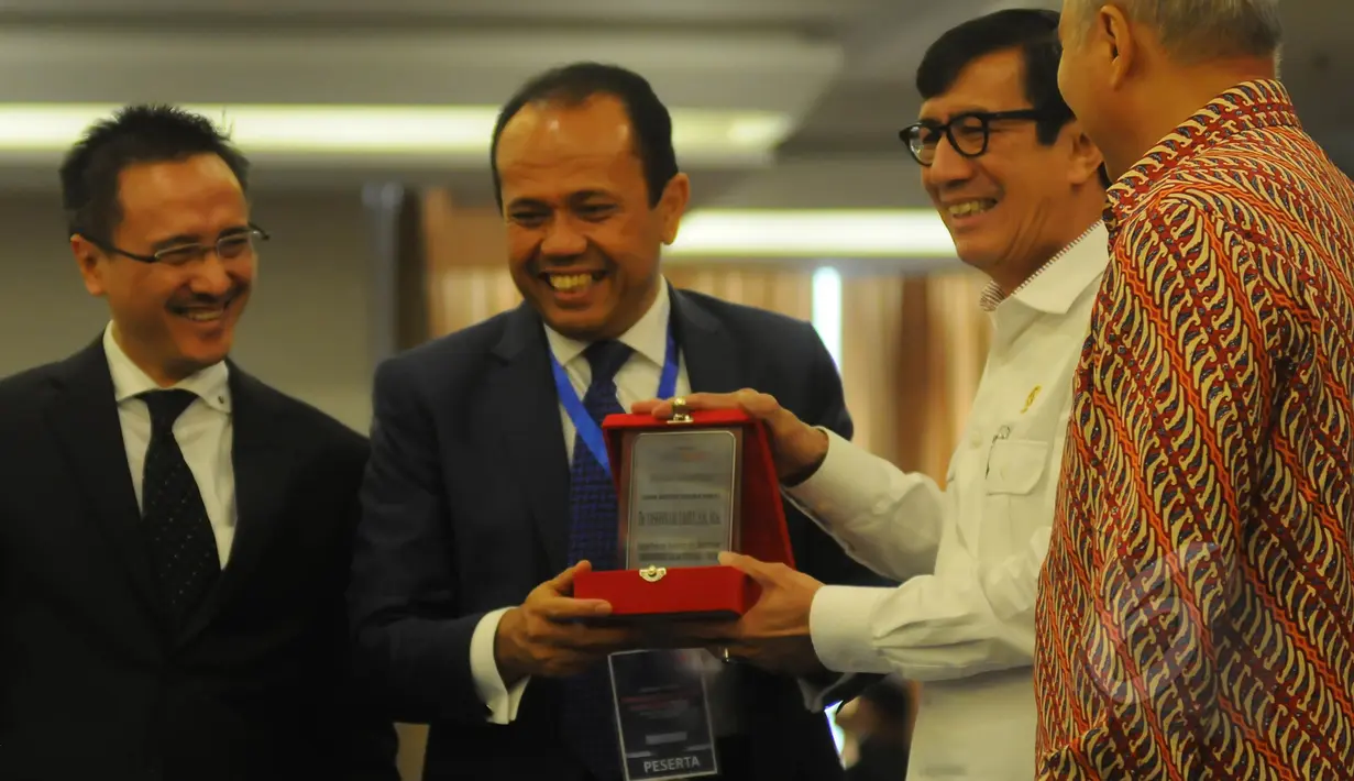 Menkumham Yasona Laoly (kedua kanan) menyerahkan cenderamata kepada ketua pembina Tekad Indonesia Juniver Girsang (kedua kiri) pada acara seminar hukum "Demokratisasi dalam Penegakan Hukum" di Jakarta, Senin (23/3/2015). (Liputan6.com/Herman Zakharia) 