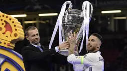 Presiden UEFA, Aleksander Ceferin, menyerahkan trofi Liga Champions kepada kapten Real Madrid, Sergio Ramos, usai menjadi juara di Stadion Millenium, Cardiff, Sabtu (3/6/2017). Madrid menang 4-1 atas Juventus. (AFP/Javier Soriano)
