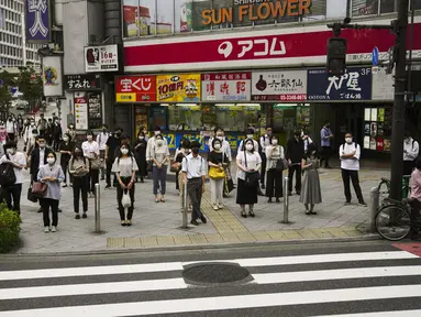 Komuter menunggu untuk menyeberang jalan menjelang Olimpiade 2020 di Tokyo, Jepang, Rabu (14/7/2021). Keadaan darurat akan berlaku sepanjang Olimpiade yang dibuka pada 23 Juli. (AP Photo/Jae C. Hong)