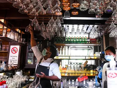 Bartender Gagan (kiri) dan seorang pelayan membersihkan bar jelang pembukaan kembali di New Delhi, 8 September 2020. Setelah sebelumnya ditutup karena pandemi COVID-19, mulai 9 September 2020 New Delhi mengizinkan bar kembali buka dengan kapasitas tempat duduk 50 persen. (Prakash SINGH/AFP)