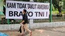 Warga melintas di depan spanduk bertulisan "Kami Tidak Takut Amerika Bravo TNI" terpampang di pagar Stasiun Gambir, Jakarta, Senin (23/10). Pemasangan spanduk ini diduga terkait undangan Panglima TNI yang ditolak masuk AS. (Liputan6.com/Faizal Fanani)