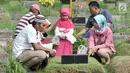 Umat muslim berdoa di makam keluarga saat ziarah kubur di Tempat Pemakaman Umum (TPU) Karet Bivak, Jakarta, Minggu (25/6). Tradisi ziarah yang dilakukan orang muslim setelah melakukan salat Idul Fitri adalah acara tahunan. (Liputan6.com/Yoppy Renato)