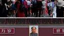 Wisatawan berdiri di depan potret mendiang pemimpin komunis Mao Zedong di Gerbang Tiananmen di Beijing pada 20 September 2019 (atas) dan polisi mengenakan masker di tengah kekhawatiran penyebaran virus corona (COVID-19) di Gerbang Tiananmen di Beijing pada 6 Maret 2020. (Greg Baker, Noel CELIS/AFP)