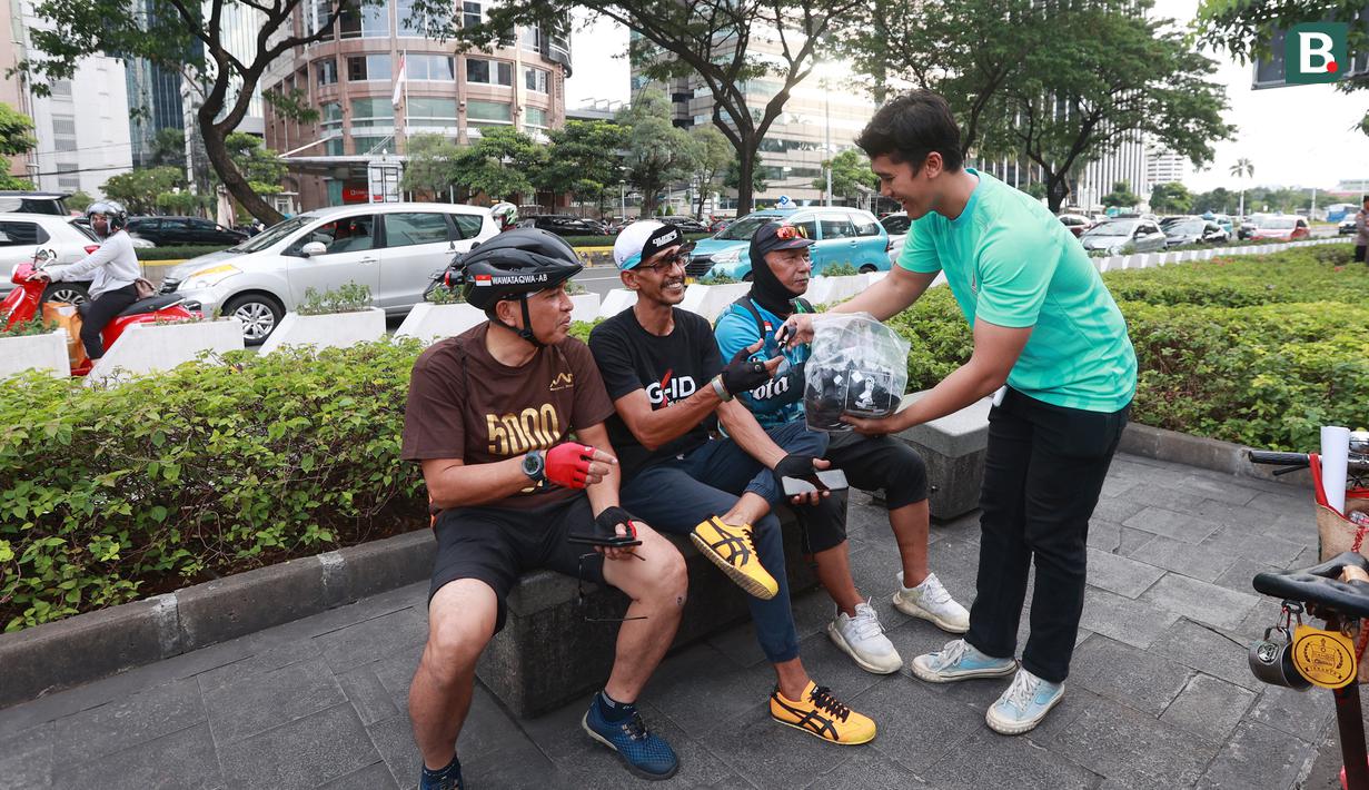 Seorang anggota komunitas Centennialz membagikan pita hitam kepada warga dalam Aksi Duka 1 Juta Pita Hitam untuk Timnas Indonesia U-20 dan Piala Dunia U-20 di trotoar FX Sudirman, Jakarta, Jumat (31/3/2023). (Bola.com/M Iqbal Ichsan)