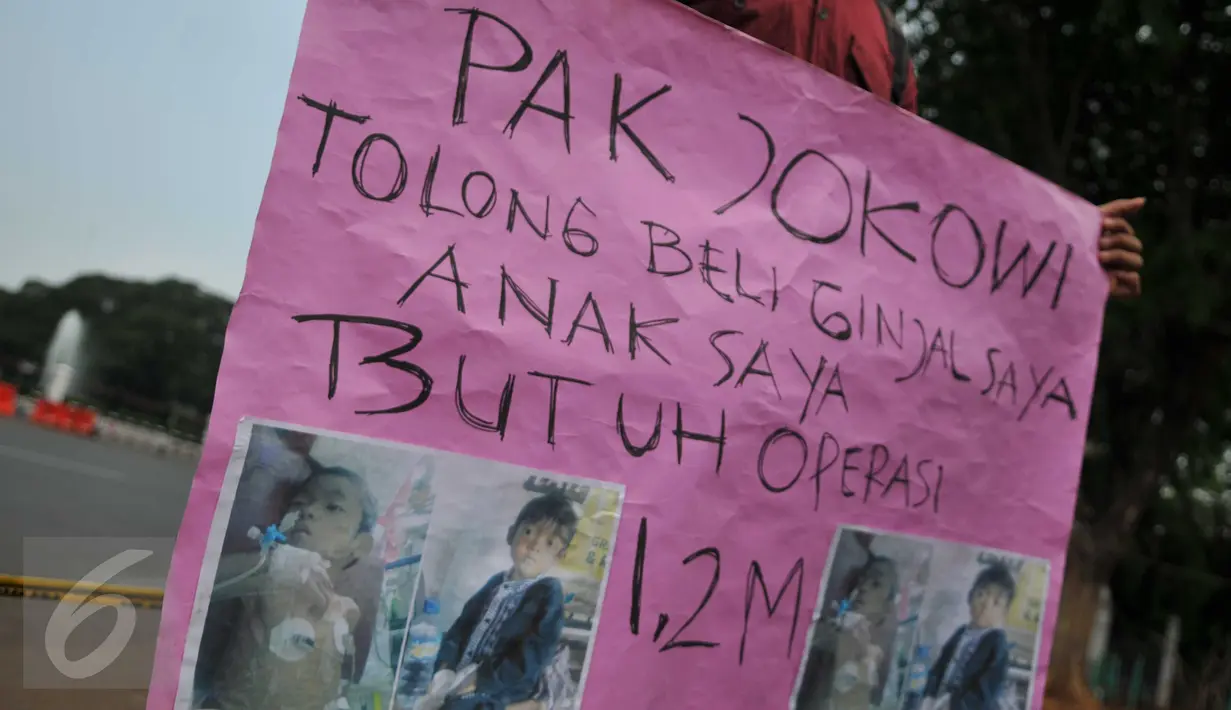 Susanto (28) memegang kertas  bertulisan: “ Pak Jokowi tolong beli ginjal saya, anak saya butuh operasi 1,2 milyar”, saat melakukan aksinya di depan Istana Merdeka, Jakarta, Jumat (20/11). (Liputan6.com/Gempur M Surya)