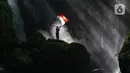 Pengunjung berdiri di atas batu besar sambil memegang bendera Merah Putih di Curug Walet, Pamijahan, Bogor, Jawa Barat, Minggu (24/12/2023). Curug yang terkenal dengan keindahannya ini berada di Desa Ciasihan, Kecamatan Pamijahan. (merdeka.com/Arie Basuki)