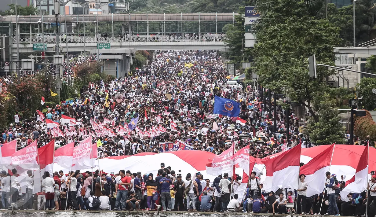 Ribuan warga berkumpul di Bundaran HI, Jakarta untuk memeriahkan aksi damai 'Kita Indonesia', Minggu (4/12). Ada banyak bendera Merah Putih dikibarkan oleh para peserta aksi hingga membuat Bundaran HI tampak memerah. (Liputan6.com/Fery Pradolo)
