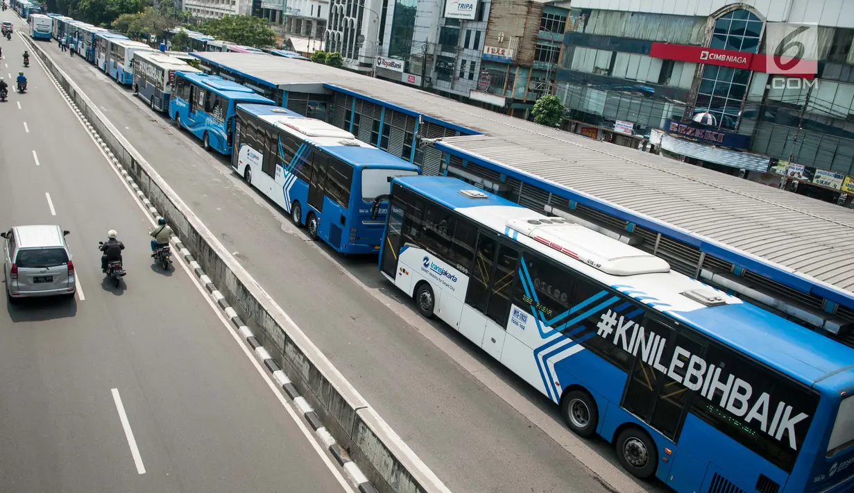 Pengendara melintas disebelah Bus Transjakarta yang mogok kerja di Halte Harmoni, Jakarta (12/6). Akbita mogok kerja ini, operasional bus Transjakarta menjadi terganggu. Kondisi itu dialami seluruh koridor bus Transjakarta. (Liputan6.com/Gempur M Surya)