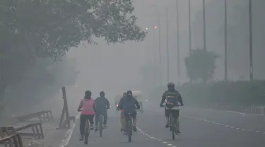 Pesepeda melintas di sepanjang jalan di tengah kondisi kabut asap yang menyelimuti New Delhi, India, Minggu (7/11/2021). Ibu kota New Delhi diselimuti udara beracun pada Sabtu kemarin karena tingkat polusi yang sangat tinggi pasca-perayaan festival besar agama Hindu. (Money SHARMA/AFP)