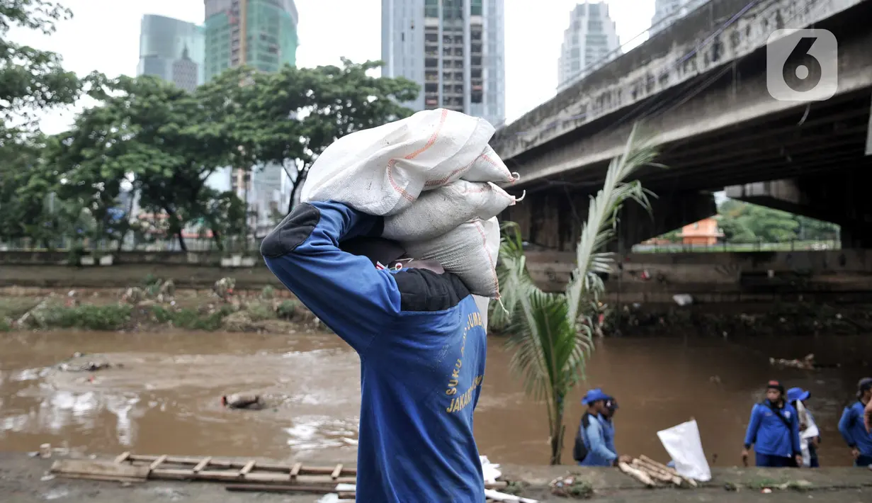 Pekerja Sudin SDA Jakpus membawa karung berisi pasir untuk penutupan titik-titik lubang rembesan di Tanggul Kanal Banjir Barat, Latuharhari, Minggu (5/1/2020). Proses penutupan cara menutup lubang rembesan dengan coran yang berisi campuran semen, pasir dan batu. (merdeka.com/Iqbal Nugroho)