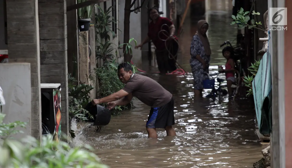 Seorang pria membuang air dengan ember saat banjir merendam kawasan Cipinang Melayu, Jakarta Timur, Senin (5/2). (Liputan6.com/Arya Manggala)