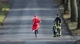 Seorang peserta berkostum Santa Claus berlari dalam kegiatan  Santa Claus Run di Michendorf, Jerman timur, Minggu (10/12). Kegiatan amal yang digelar setiap tahun ini diikuti ribuan warga Jerman dan wisatawan mancanegara. (Ralf Hirschberger / dpa / AFP)