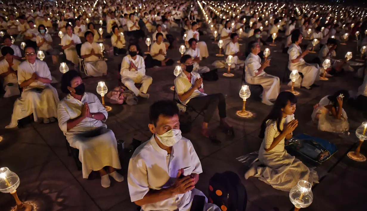 Umat Buddha mengenakan masker saat berdoa bersama di kuil Buddha Wat Dhammakaya, Bangkok (31/1/2020). Pemerintah Thailand mengumumkan 14 orang terkonfirmasi infeksi virus corona.Thailand memiliki jumlah kasus terbesar kedua di luar China. (AFP Photo/Lillian Suwanrumpha)