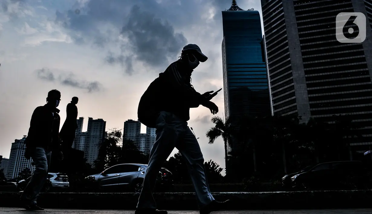 Pekerja melintasi trotoar saat jam pulang kantor di kawasan Sudirman, Jakarta, Senin (14/9/2020). Selama PSBB, Pemprov DKI Jakarta mewajibkan perusahaan nonesensial untuk membatasi 25 persen dari total pekerja yang bekerja di kantor guna memutus penyebaran Covid-19. (merdeka.com/Iqbal S. Nugroho)