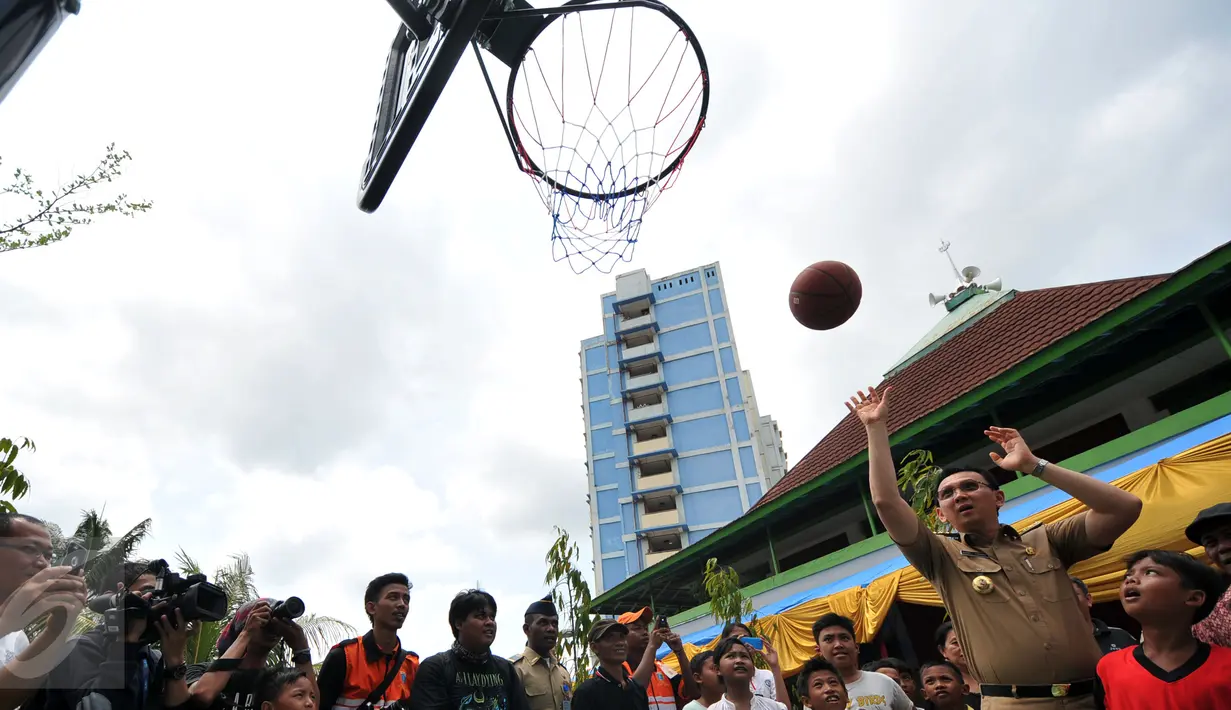 Gubernur DKI Jakarta Basuki T Purnama saat menjajal memasukkan bola ke dalam ring basket seusai meresmikan Ruang Publik Terpadu Ramah Anak (RPTRA) Intiland Teduh, Karet Tengsin, Jakarta, Rabu (30/12). (Liputan6.com/Yoppy Renato)