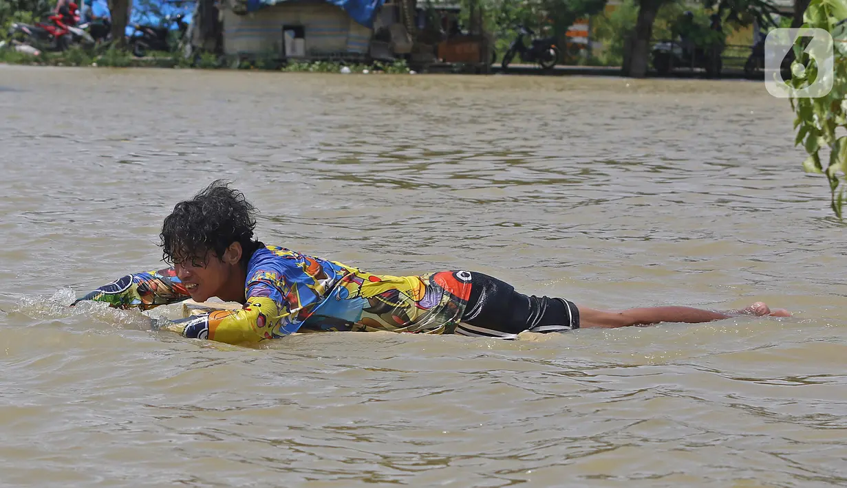 Seorang warga berada berenang saat banjir di Desa Sukalaksana Kabupaten Bekasi, Jawa Barat, Senin (22/02/2021). Banjir tersebut akibat luapan sungai Citarum yang tanggulnya jebol. (Liputan6.com/Herman Zakharia)