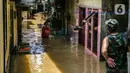 Warga menyusuri banjir yang merendam permukiman di kawasan Kampung Melayu, Jakarta, Selasa (9/2/2021). Banjir yang berangsur surut dimanfaatkan warga untuk membersihkan rumah dan barang-barang dari endapan lumpur. (Liputan6.com/Faizal Fanani)