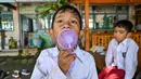 Seorang siswa menggunakan kipas angin portabel saat belajar di luar kelas selama gelombang panas di sebuah sekolah dasar di Banda Aceh pada 7 Mei 2024. (CHAIDEER MAHYUDDIN/AFP)