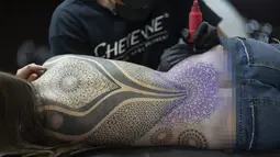 Seorang wanita terbaring saat ditato dalam acara Sao Paulo Tattoo Week, Brasil, Jumat (25/10/2019). (AP Photo/Andre Penner)