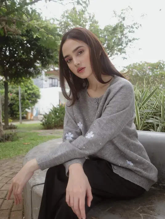 Syifa tampil mengenakan atasan cardigan abu-abu dipadukan celana hitam panjang. Rambut panjang kecoklatannya dibiarkan terurai dengan wajah dipulas makeup warm. [@syifahadju]