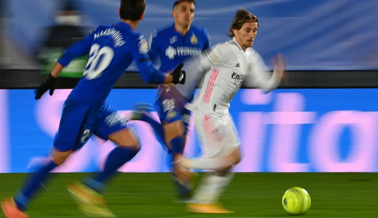 Gelandang Real Madrid, Luka Modric (kanan) menggiring bola dari kawalan para pemain Getafe pada pertandingan lanjutan La Liga Spanyol di stadion Alfredo di Stefano di Madrid, Spanyol, Rabu (10/2/2021).  EL Real kini mendekati posisi tim tetangga, Atletico Madrid. (AFP/Gabriel Bouys)