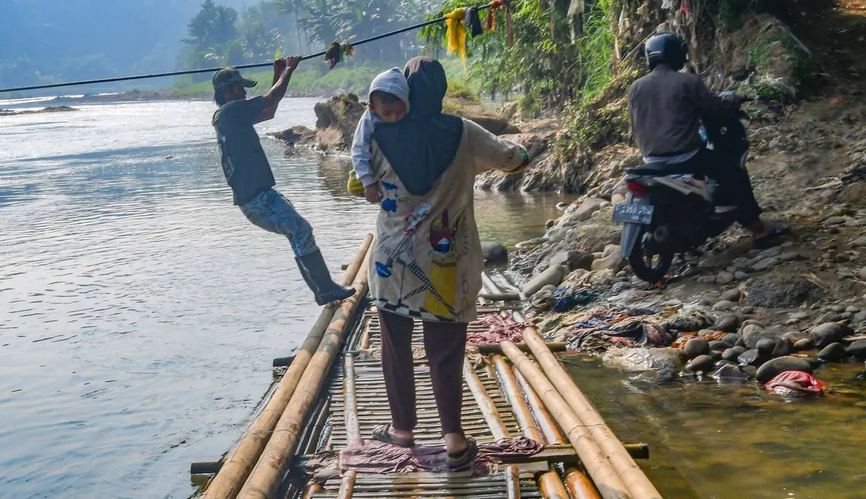 Warga bersiap turun usai menyeberangi Sungai Cisadane menggunakan rakit bambu di kawasan Ciseeng, Kabupaten Bogor, Jawa Barat, Kamis (11/6/2026). (merdeka.com/Arie Basuki)