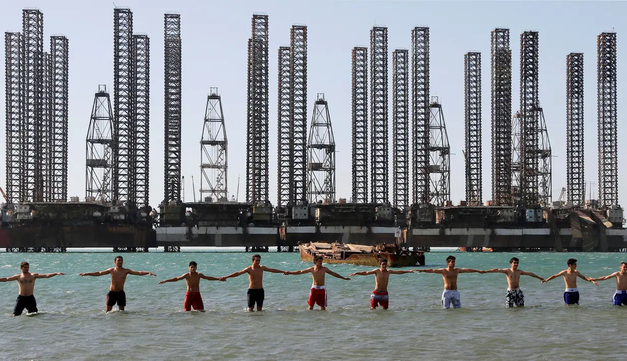 Anak-anak yang tergabung dalam sekolah kickboxing sedang berlatih di tepi Laut Kaspia dekat dengan bekas tempat pengeboran minyak era Soviet di kota Baku, Azerbaijan, Sabtu (27/6). (AP Photo/Dmitry Lovetsky)