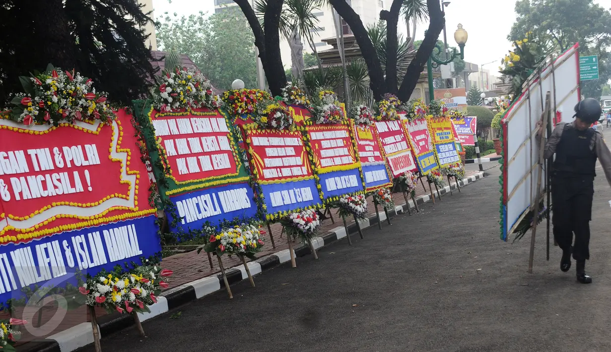 Petugas memindahkan karangan bunga yang diletakkan di depan Mabes Polri, Jakarta, Rabu (3/5). Ratusan karangan bunga itu terus berdatangan dan mengelilingi gedung Mabes Polri di Jalan Trunojoyo Jakarta Selatan. (Liputan6.com/Helmi Fithriansyah)