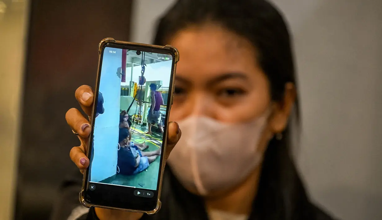 Seorang wanita memperlihatkan rekaman video suaminya sambil menunggu kabar terbaru tentang operasi pencarian dan penyelamatan kapal penumpang Mutiara Sentosa 2 di pelabuhan Tanjung Perak, Minggu (2/8/2026). (AFP/ Juni Kriswanto)
