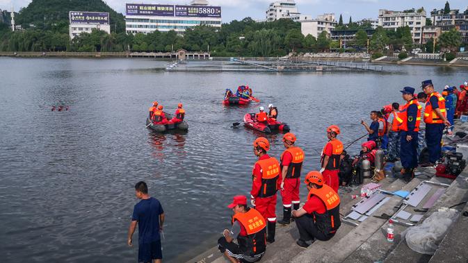 Tim penyelamat mencari korban selamat dari sebuah bus yang jatuh ke danau di Anshun, provinsi Guizhou, China, Selasa (7/7/2020). Sedikitnya 21 orang tewas usai bus yang membawa siswa untuk mengikuti ujian masuk perguruan tinggi atau gaokao itu menabrak pagar pembatas lalu tercebur ke danau (STR/AFP)