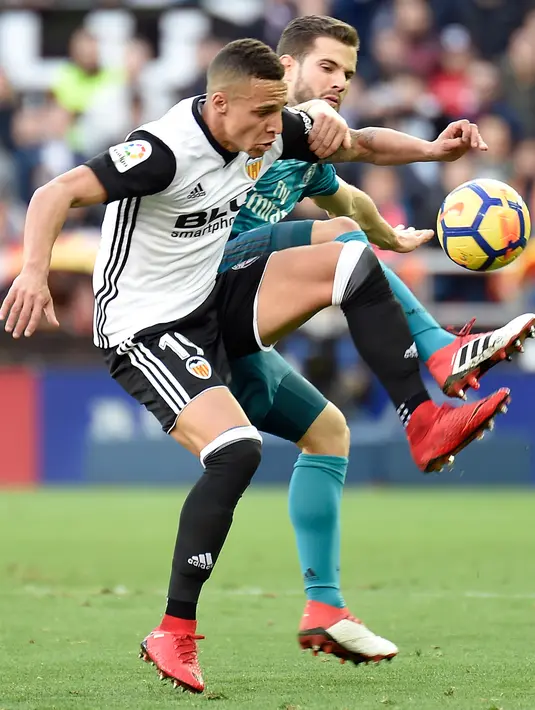 Bek Real Madrid Nacho Fernandez (kanan) berusaha merebut bola penyerang Valencia, Rodri saat bertanding pada lanjutan La Liga Spanyol di stadion Mestalla, (27/1). Real Madrid menang 4-1. (AFP Photo/Jose Jordan)
