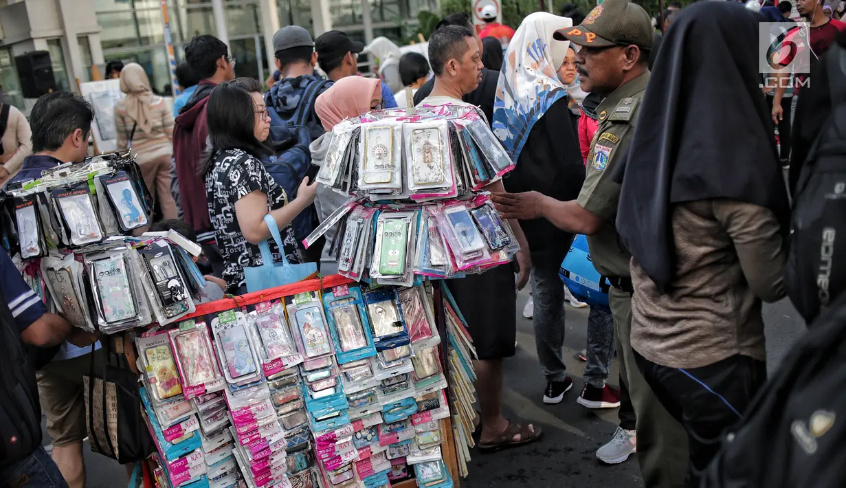 Petugas Satpol PP menertibkan PKL yang berdagang di kawasan Car Free Day, Bundaran HI, Jakarta, Minggu (5/5/2019). Kurangnya pengawasan menyebabkan banyak PKL berjualan tidak pada tempat yang telah di sediakan Pemprov DKI sehingga mengganggu aktivitas warga berolahraga. (Liputan6.com/Faizal Fanani)