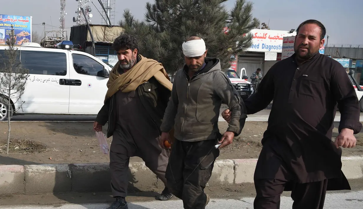 Warga Afghanistan membantu seorang pria terluka di dekat lokasi serangan bom mobil bunuh diri yang menargetkan tentara asing di Kabul (2/3). Serangan ini terjadi sekitar pukul 09:00. (AFP Photo/Wakil Kohsar)