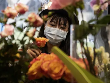 Penjual bunga Zhao Yuanyuan mengenakan masker mengatur bunga menjelang Hari Valentine di tokonya di Shanghai (12/2/2020). Wabah virus corona COVID-19 masih membayangi perayaan Hari Valentine di negara China. (AFP Photo/Noel Celis)