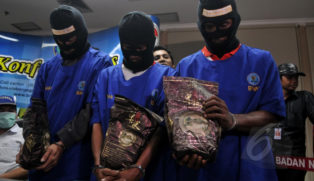 Tiga tersangka memegang barang bukti sabu saat konferensi pers di Kantor BNN, Jakarta, Kamis (16/4/2015). BNN menggagalkan transaksi narkotika jenis sabu seberat 10 kg dari Malaysia ke Indonesia. (Liputan6.com/Johan Tallo)