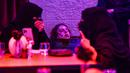 Pengunjung tertawa ketika penyangga kepala zombie ditempatkan di dekat meja mereka di restoran "Shadows" bertema horor di Riyadh, Arab Saudi, 19 Januari 2022. Restoran tersebut menawarkan pelanggan hidangan dengan tengkorak dan darah ditemani zombie serta vampir (Fayez Nureldine/AFP)
