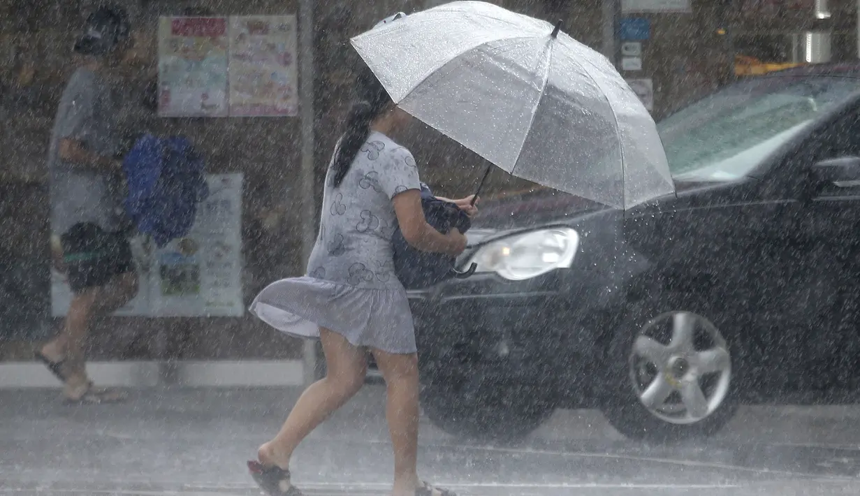 Seorang wanita Taiwan mengenakan payung berjalan melawan hembusan angin kencang yang ditimbulkan oleh topan Lekima di Taipei, Taiwan, Jumat (9/8/2019). Topan Lekima saat ini tengah menghantam Taiwan, membawa angin ribut dengan kecepatan 190 km/jam. (AP Photo / Chiang Ying-ying)