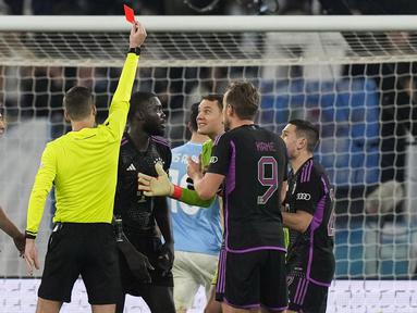 Wasit Francois Letexier memberikan kartu merah kepada pemain Bayern Munchen, Dayot Upamecano (tengah) setelah melakukan pelanggaran terhadap pemain Lazio, Gustav Isaksen di dalam kotak penalti pada laga leg pertama 16 besar Liga Champions 2023/2024 di Olympic Stadium, Roma, Italia, Kamis (15/02/2024) WIB. (AP Photo/Andrew Medichini)