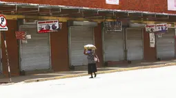 Seorang wanita berjalan di jalan yang sepi di Harare, Zimbabwe, Selasa (5/1/2021). Zimbabwe memulai lockdown selama 30 hari dalam upaya untuk mengendalikan lonjakan infeksi COVID-19 yang mengancam petugas kesehatan. (AP Photo/Tsvangirayi Mukwazhi)